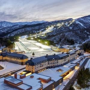 Vue aérienne d'une grande station de ski illuminée au pied de montagnes enneigées au crépuscule