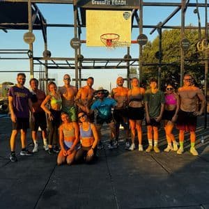 Un gruppo WeRoad in posa per una foto in una palestra CrossFit all'aperto con un canestro da basket sullo sfondo.