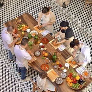 An overhead view of a WeRoad group trip participating in a cooking class, preparing fresh vegetables on a large wooden table.