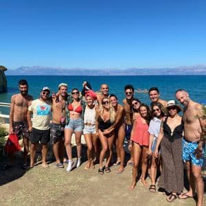 Un viaje en grupo de WeRoad posando juntos en ropa de playa en un día soleado, con acantilados y el mar de fondo.