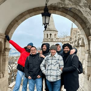 Un voyage de groupe WeRoad de six personnes posant pour une photo sous une arche en pierre, avec une tourelle de château visible en arrière-plan.
