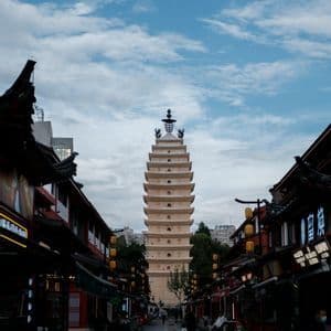 Una pagoda alta e a più livelli si erge alla fine di una strada lastricata fiancheggiata da edifici tradizionali sotto un cielo nuvoloso.