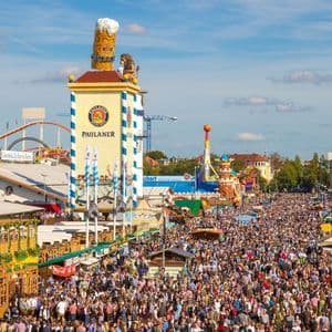 Una veduta aerea di una folla immensa che riempie le strade di un festival all'aperto con grandi tende e giostre.