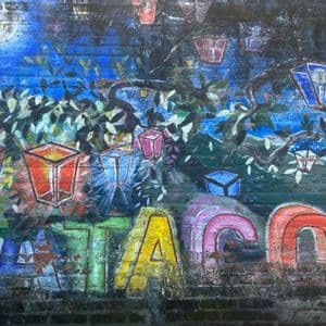 Ein farbenfrohes Graffiti-Wandbild auf einer Ziegelmauer, das einen Baum mit leuchtenden Laternen an den Ästen unter einem Vollmond zeigt.