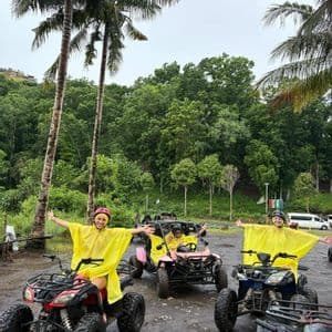 Un gruppo WeRoad in viaggio con poncho antipioggia gialli, in posa su quad e un buggy nella giungla tra le palme.