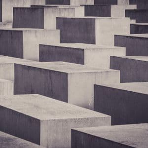 Vista cenital monocromática de numerosos bloques rectangulares de hormigón de distintas alturas dispuestos en una densa cuadrícula.