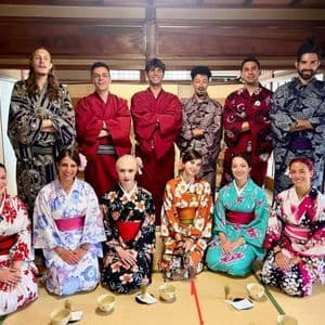 Un gruppo WeRoad in viaggio, con indosso kimono e yukata tradizionali, posa insieme in una stanza giapponese con tatami.