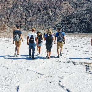 Un viaggio di gruppo WeRoad attraversa una vasta distesa di sale bianca con montagne rocciose sullo sfondo.