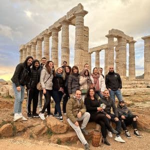 Un viaggio di gruppo WeRoad in posa per una foto su una collina rocciosa con antiche rovine di templi sullo sfondo.
