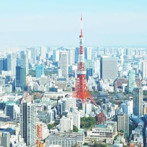 Vue aérienne d'une tour en treillis rouge et blanc au centre d'un paysage urbain dense avec de nombreux gratte-ciel.