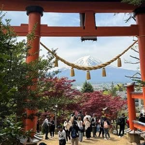 Un viaggio di gruppo WeRoad si riunisce sotto un grande cancello torii rosso per ammirare una montagna innevata in lontananza.