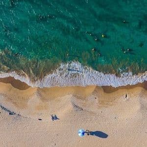 Vista aerea di una spiaggia dove le persone nuotano nel mare turchese e si rilassano sulla sabbia.