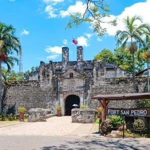 L'ingresso al Forte San Pedro, un forte storico in pietra con un portale ad arco, affiancato da palme sotto un cielo azzurro.