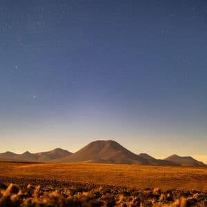 Una vasta pianura desertica con montagne ondulate in lontananza sotto un cielo notturno limpido e stellato.