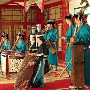 Eine Gruppe von Musikern in traditioneller mongolischer Kleidung spielt verschiedene Saiten- und Schlaginstrumente auf einer farbenfrohen, verzierten Bühne.