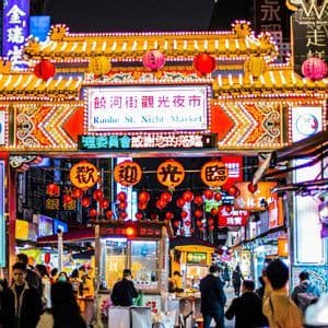 L'ingresso splendidamente illuminato del mercato notturno di Raohe St., affollato di gente e decorato di notte con lanterne rosse luminose.