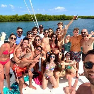 A WeRoad group trip smiling and posing for a group selfie on the deck of a boat on a sunny day.