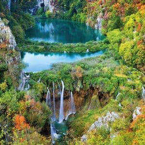 Des cascades se déversent dans des lacs turquoise, entourés d'une forêt dense aux couleurs automnales.