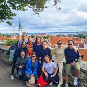 Un gruppo WeRoad in posa per una foto da un punto panoramico in pietra che domina una città con tetti rossi e un campanile.