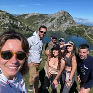 Un viaje en grupo de WeRoad posa para una selfie en un día soleado con un lago de montaña de fondo.