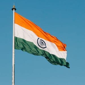 La bandiera tricolore dell'India sventola su un pennone contro un cielo azzurro e limpido.