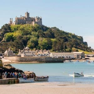 Un viaggio di gruppo WeRoad si riunisce su un molo per imbarcarsi su delle barche in un porto sotto un castello su una collina boscosa.