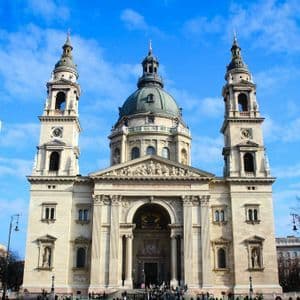 Die beeindruckende Fassade einer neoklassizistischen Basilika mit zentraler Kuppel und zwei Glockentürmen unter blauem Himmel.