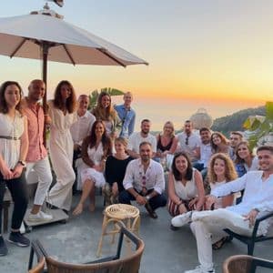 Un viaje en grupo de WeRoad posando para una foto en una terraza en la azotea con vistas al mar al atardecer.