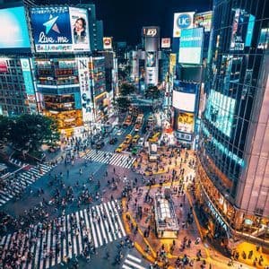 Una vista aerea di un frenetico incrocio cittadino di notte, con folle di persone e auto che si incrociano sotto luminose insegne al neon.