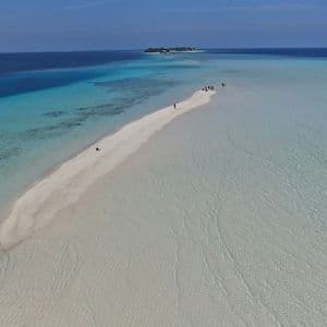 Una vista aerea di un viaggio di gruppo WeRoad che cammina lungo una lunga lingua di sabbia bianca circondata da acqua cristallina color turchese, con una piccola isola in lontananza.