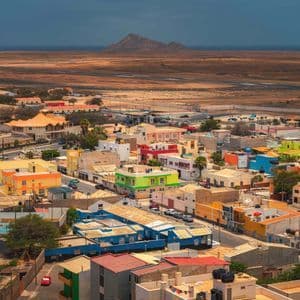 Vue en hauteur d'une ville colorée avec des bâtiments bas dans un vaste paysage aride avec une montagne à l'horizon.