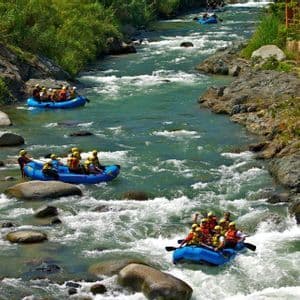 Un viaggio di gruppo WeRoad: rafting su gommoni blu lungo un fiume immerso nella vegetazione lussureggiante.