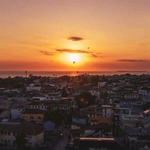 Un tramonto arancione sull'oceano illumina i tetti di una città di mare.
