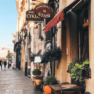 Uno scooter è parcheggiato su una stretta strada di ciottoli fiancheggiata da edifici storici, con un'antica torre di chiesa visibile sullo sfondo.
