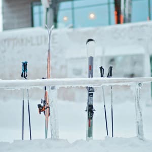 Ski und Stöcke stehen im tiefen Schnee und lehnen an einem vollständig mit Eis und Schnee bedeckten Gestell.