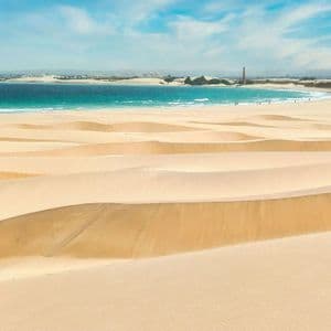 Un viaggio di gruppo WeRoad tra ampie dune di sabbia, affacciate su un oceano turchese sotto un cielo parzialmente nuvoloso.