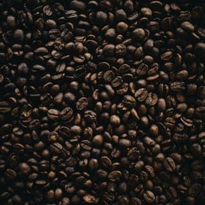 Primo piano, vista dall'alto, di chicchi di caffè tostato scuro che riempiono l'intera immagine.