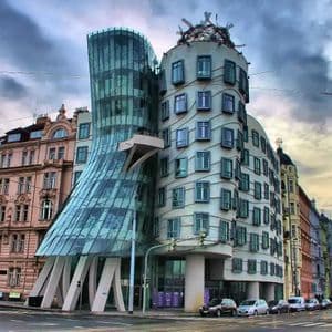 El moderno edificio de la Casa Danzante, con sus retorcidas torres de cristal y hormigón ondulado, se alza en una esquina de una calle de la ciudad bajo un cielo nublado.