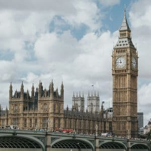 La torre dell'orologio Big Ben e il Parlamento, visti da un ponte vivace sotto un cielo nuvoloso.