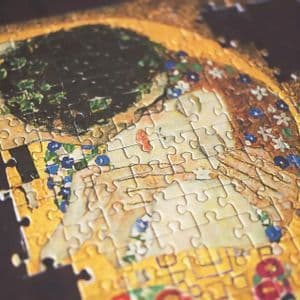Una vista de cerca, en ángulo, de un rompecabezas incompleto con la pintura de Gustav Klimt, El Beso.