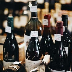 Several bottles of red wine with price tags are displayed for sale in a wine shop.