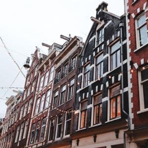 Una veduta dal basso di tradizionali case a capanna in mattoni scuri e rossi, con file di luci appese su una strada.