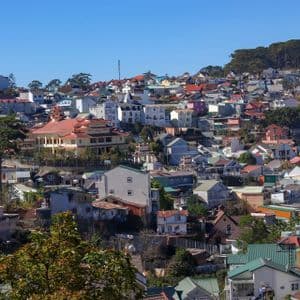 Un'ampia veduta di un borgo collinare fittamente costruito, con case e palazzi colorati sotto un cielo azzurro e limpido.