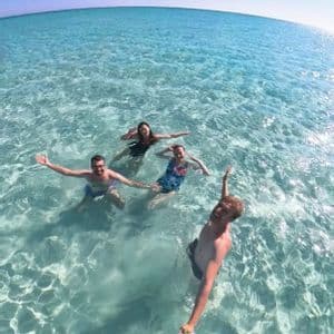 Un viaggio di gruppo WeRoad di quattro persone che si scattano un selfie mentre nuotano in acque limpide e turchesi sotto un cielo azzurro.