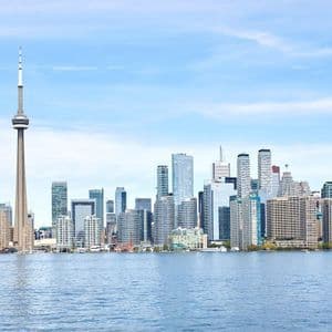 Uno skyline moderno con un'alta torre di osservazione e grattacieli, visibile dall'acqua sotto un cielo azzurro e limpido.