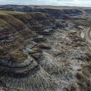 Una veduta aerea di un vasto paesaggio di calanchi, con colline erose che mostrano strati sedimentari visibili e una strada tortuosa.