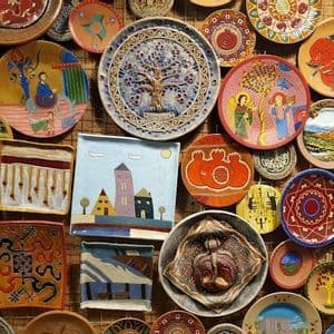 A collection of colorful, hand-painted ceramic plates and tiles with intricate designs covering a wall.