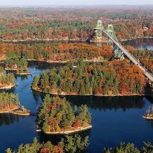 Una vista aerea di un grande ponte verde che attraversa uno specchio d'acqua con molte piccole isole coperte di fogliame autunnale.