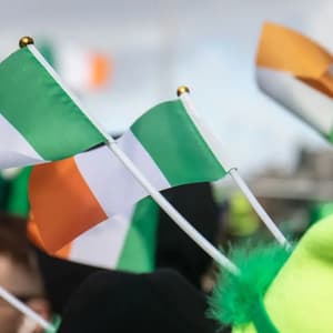 Primo piano di piccole bandiere irlandesi innalzate tra la folla durante una festa.