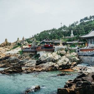Un complesso di templi asiatici tradizionali con un ponte di pietra, costruito su una scogliera rocciosa a picco sul mare.